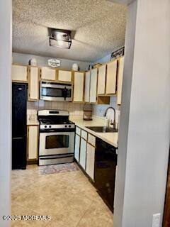 kitchen with light countertops, appliances with stainless steel finishes, a sink, and light floors