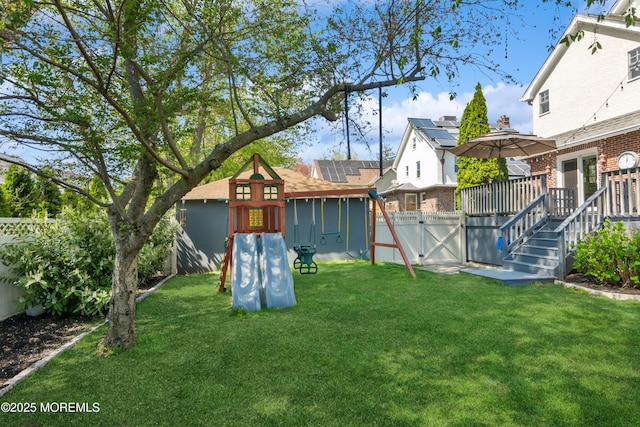 view of yard featuring a gate, a playground, a deck, and a fenced backyard