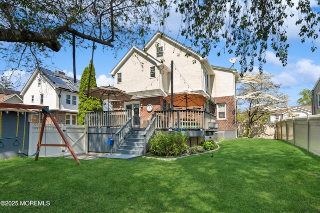 rear view of house featuring a yard, brick siding, a wooden deck, and a fenced backyard