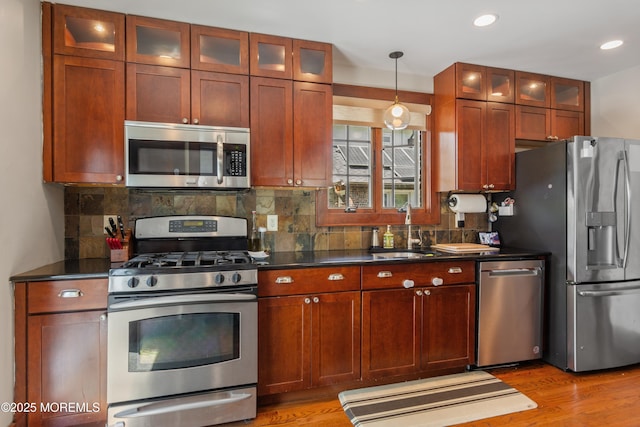 kitchen with dark countertops, light wood finished floors, appliances with stainless steel finishes, and a sink