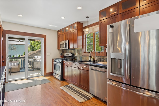 kitchen with a sink, stainless steel appliances, dark countertops, and recessed lighting