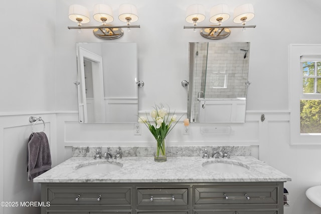 full bath featuring double vanity, a tile shower, and a sink