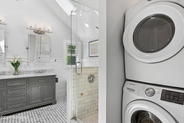 bathroom with a stall shower, lofted ceiling, stacked washer and clothes dryer, and vanity