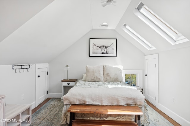 bedroom featuring baseboards, visible vents, vaulted ceiling with skylight, and wood finished floors