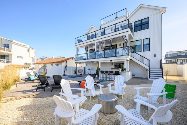 back of property featuring stairs, an outdoor fire pit, a fenced backyard, a patio area, and a balcony