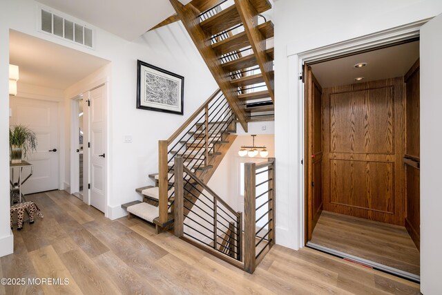 stairs featuring a notable chandelier, wood finished floors, and visible vents