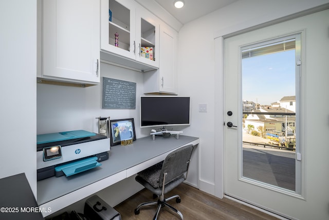office space with plenty of natural light, built in desk, and dark wood-type flooring