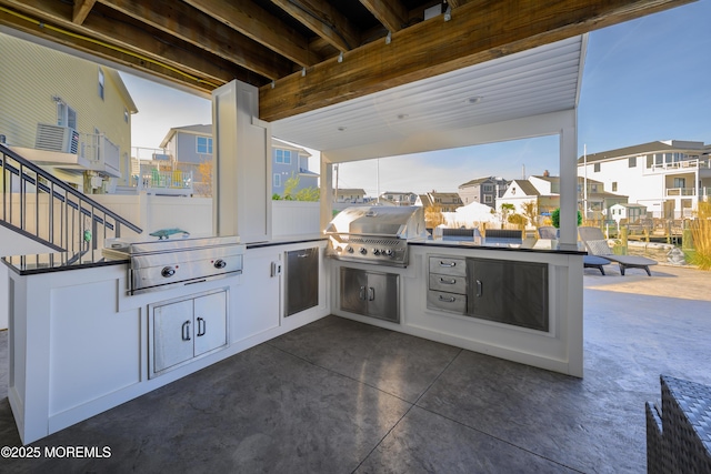 view of patio featuring an outdoor kitchen, a grill, and a residential view