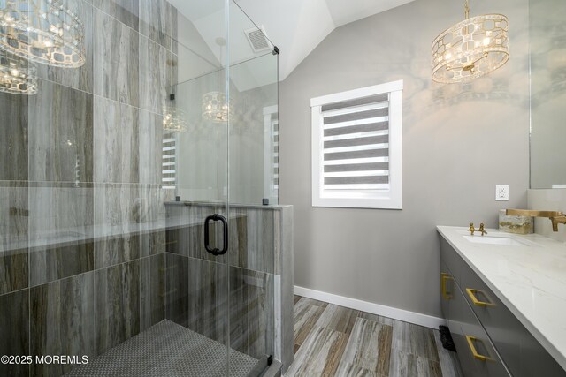 bathroom with a shower stall, vanity, baseboards, lofted ceiling, and an inviting chandelier