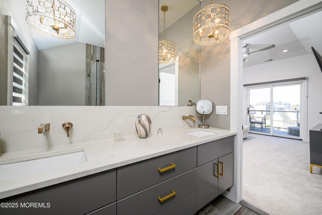 full bathroom featuring double vanity, a sink, and ceiling fan with notable chandelier