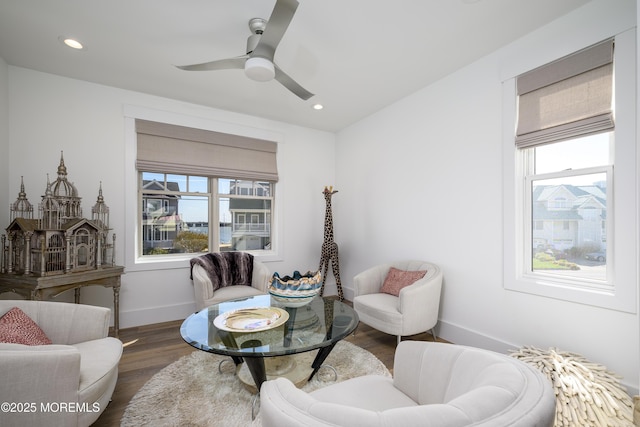sitting room with a ceiling fan, baseboards, a wealth of natural light, and wood finished floors