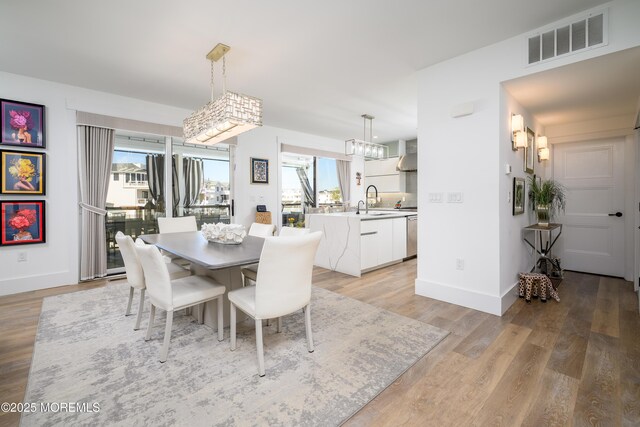 dining area featuring baseboards, visible vents, a healthy amount of sunlight, and light wood finished floors