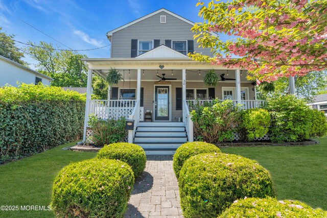 view of front facade featuring a porch, ceiling fan, stairway, and a front yard