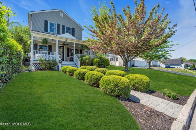 view of front facade with covered porch, ceiling fan, central AC, a front lawn, and stairs