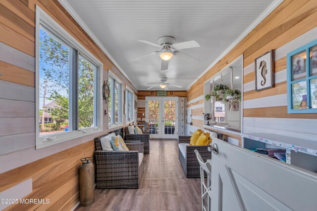 sunroom / solarium featuring wood walls, ornamental molding, french doors, and wood finished floors