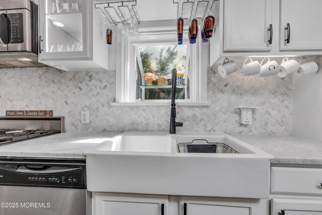 kitchen featuring a sink, appliances with stainless steel finishes, backsplash, and white cabinetry