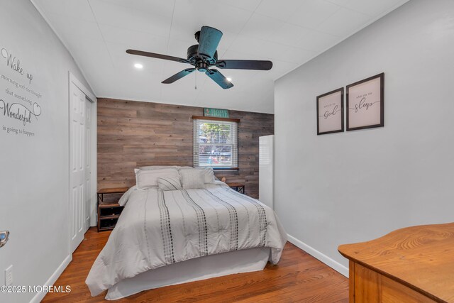 bedroom with wooden walls, baseboards, wood finished floors, and an accent wall