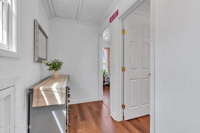 hall featuring baseboards, ornamental molding, and wood finished floors