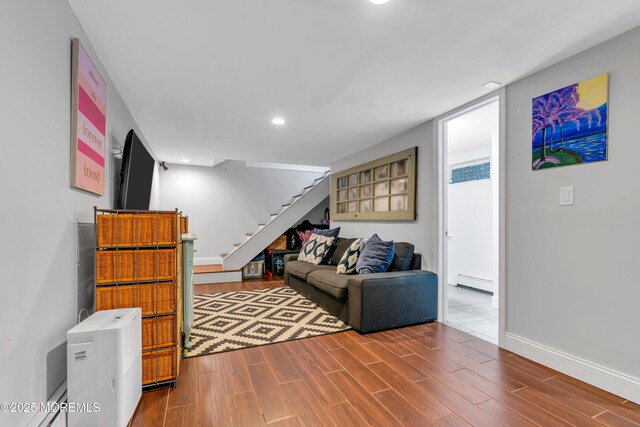 living area with stairs, recessed lighting, baseboards, wood finished floors, and a baseboard radiator