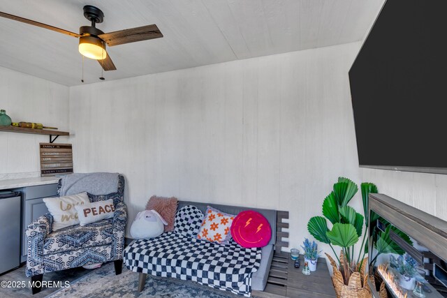 living area with wooden walls and ceiling fan