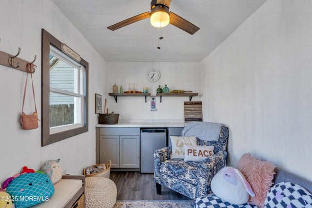 living area featuring a ceiling fan and dark wood finished floors