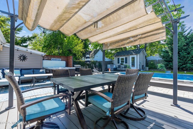 deck featuring outdoor dining area, an outdoor pool, an outdoor structure, a fenced backyard, and an outdoor hangout area