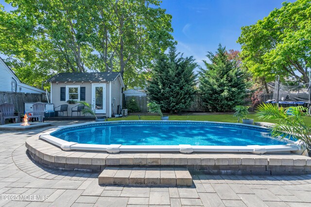 view of swimming pool featuring a fenced in pool, a trampoline, an outbuilding, and a fenced backyard