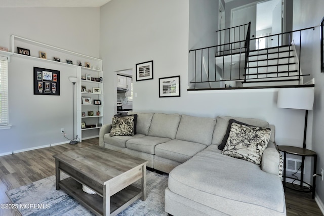 living area featuring stairs, high vaulted ceiling, baseboards, and wood finished floors