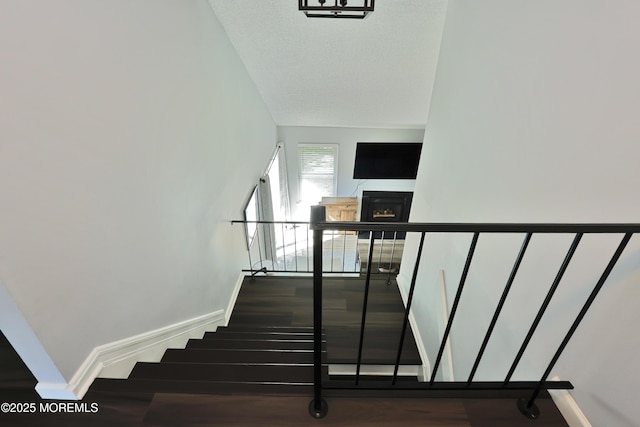 stairs featuring baseboards, wood finished floors, and a fireplace