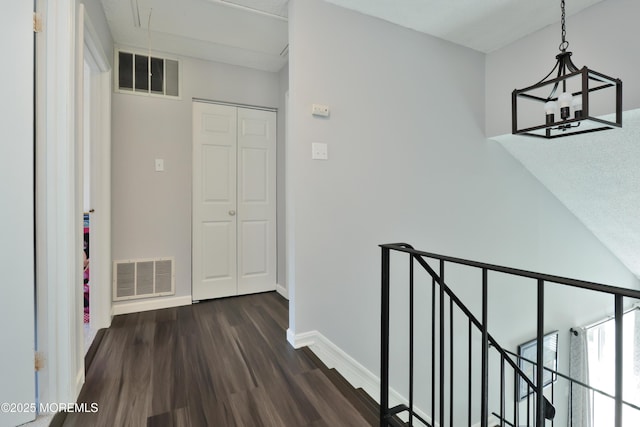hallway with baseboards, visible vents, an upstairs landing, and dark wood-type flooring