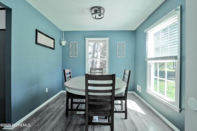 dining room with baseboards, a textured ceiling, and wood finished floors