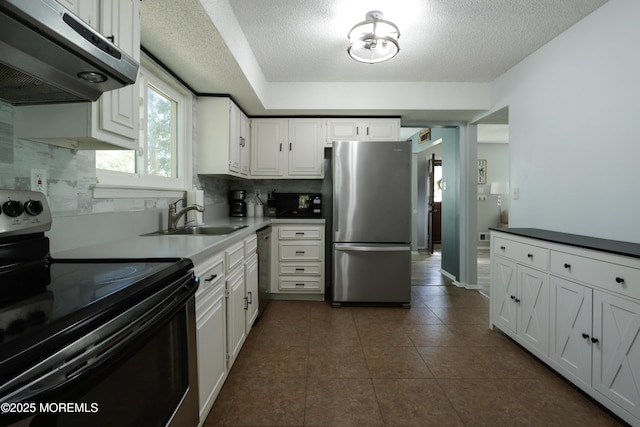 kitchen featuring decorative backsplash, a textured ceiling, range hood, a sink, and stainless steel appliances