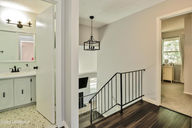 staircase with baseboards, wood finished floors, and an inviting chandelier