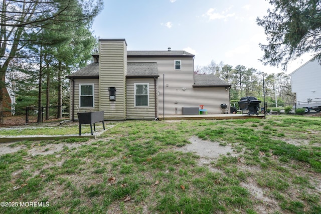 back of property with fence, a wooden deck, a chimney, and central AC unit