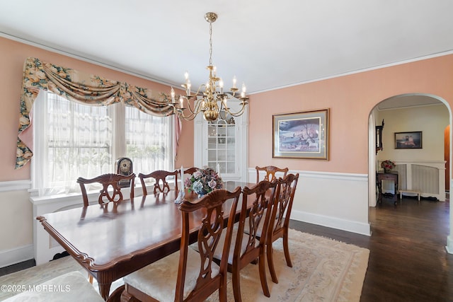 dining space featuring an inviting chandelier, ornamental molding, wood finished floors, radiator heating unit, and arched walkways