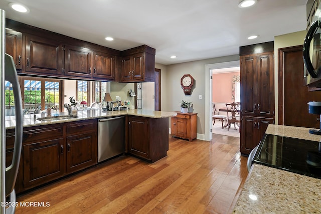 kitchen featuring light stone countertops, a sink, dishwasher, recessed lighting, and light wood-type flooring