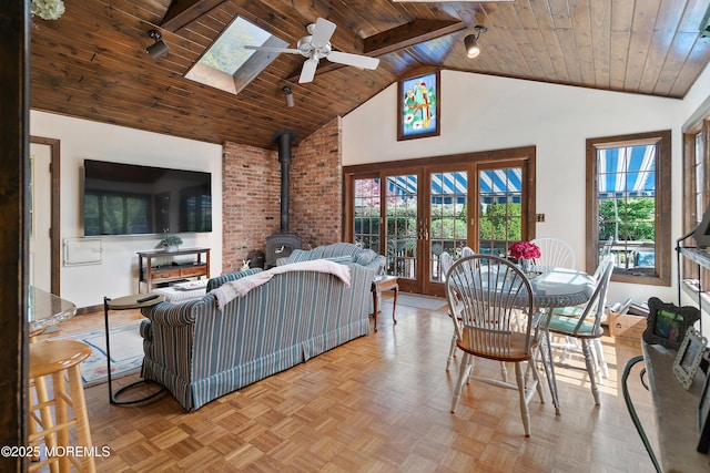 living room with wood ceiling, ceiling fan, french doors, a skylight, and a wood stove