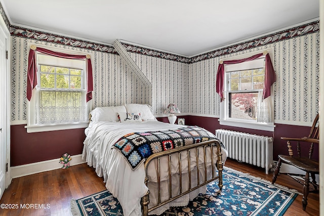 bedroom featuring wallpapered walls, baseboards, radiator, and wood finished floors