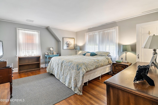 bedroom featuring ornamental molding, wood finished floors, and visible vents