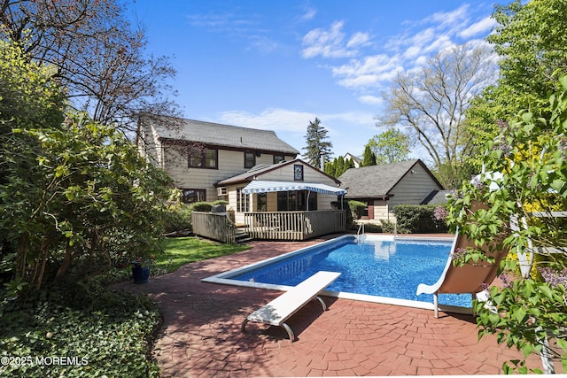 view of pool with a fenced in pool, a wooden deck, a diving board, and a patio area