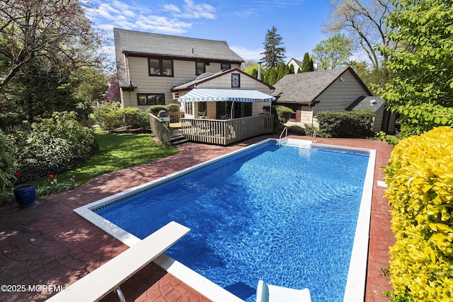 view of swimming pool featuring a fenced in pool, a wooden deck, a diving board, and a patio