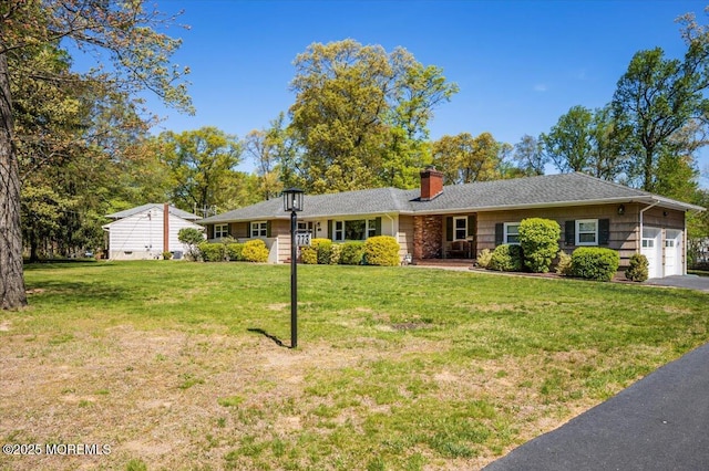 ranch-style house featuring an attached garage, driveway, a front yard, and a chimney