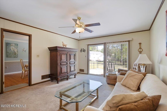 living area with ceiling fan, visible vents, crown molding, baseboards, and light carpet