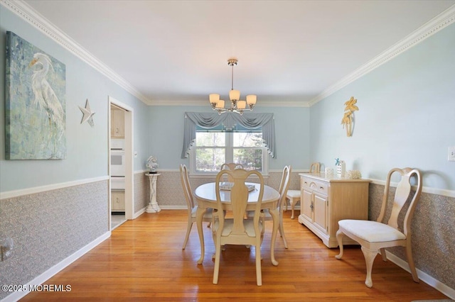 dining space featuring an inviting chandelier, crown molding, and light wood finished floors