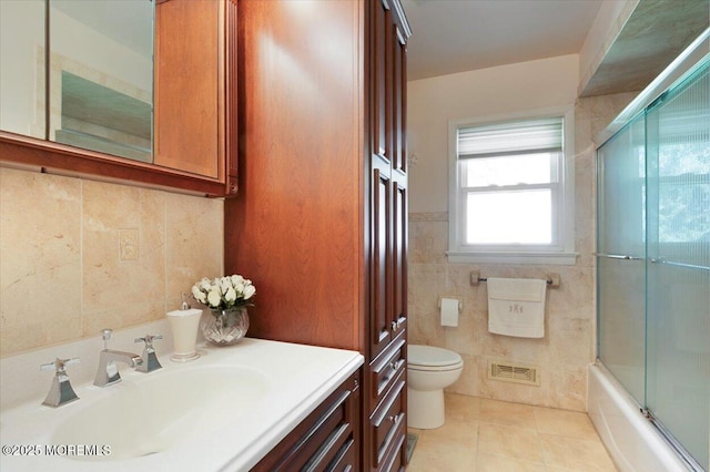 bathroom with tile patterned flooring, vanity, visible vents, toilet, and tile walls