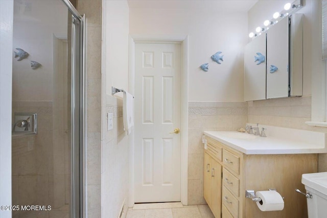 bathroom featuring vanity, toilet, tile patterned floors, tile walls, and a stall shower