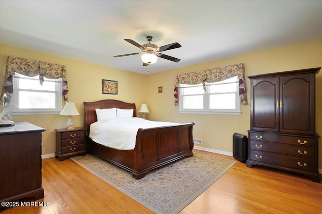 bedroom with a ceiling fan, baseboards, and light wood-type flooring
