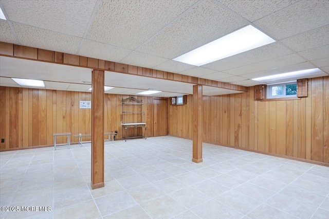 below grade area with wood walls and a paneled ceiling
