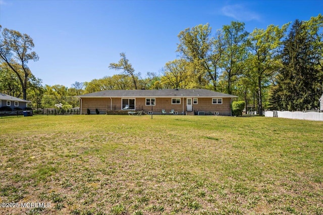rear view of property featuring a yard and fence