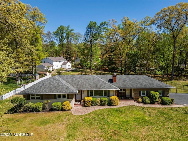 ranch-style home featuring a chimney, fence, and a front yard